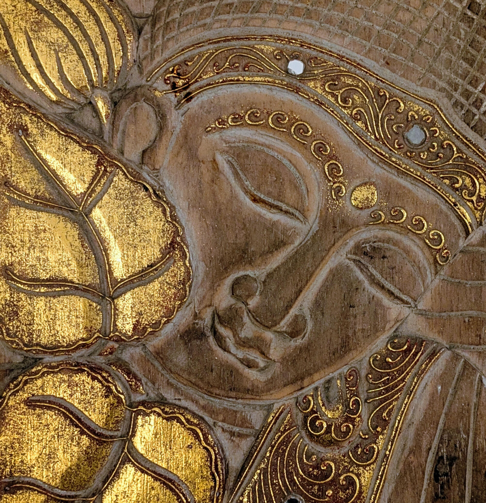 Click here for Mango apartment Close-up of carved Buddha wall art with gold accents.
